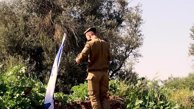 Patriotism in the IDF (Israel Defense Forces): Israeli Soldier climbing to the top of a mountain kisses and salutes the Flag of Israel. Slow Motion Video Effect