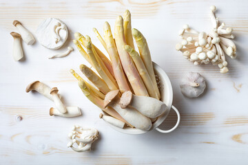 Raw white asparagus and mushrooms on wooden table. White food ingredients still life. Top view