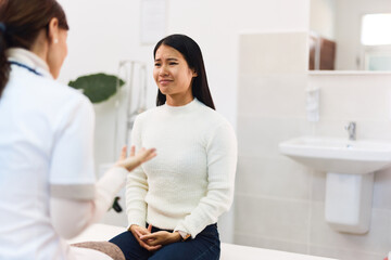 A pretty Asian female patient sitting with a female doctor in the ambulance.