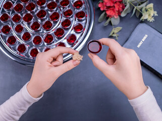 Closeup of young woman taking communion from small cups on black background