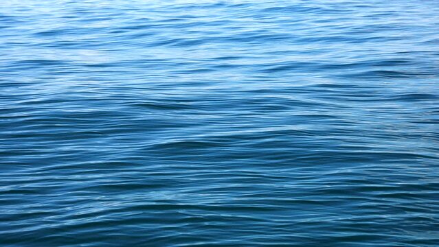 Slow motion of the waves with ripples on the blue water surface of the deep sea. Calm meditative background