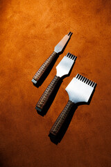 Obraz premium Tools for making leather goods and pieces of brown leather. Production of leather products. View from above
