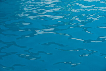 Fototapeta na wymiar Ripped water in swimming pool. Surface of blue swimming pool, background of water.