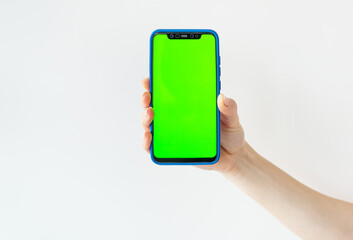 Mockup image, girl holding smartphone with blank green screen on white wall. Ready mockup for designers.