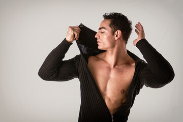 Confident, attractive young man with open sweater on muscular torso