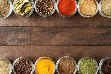 Various kinds of spices in bowls on wooden table with copyspace. Top view