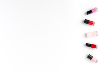 Red and pink nail polishes on white background with copyspace. Top view