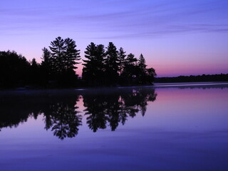 Summer sunrise from a pontoon boat on the mirror smooth water surface with a perfect purple...