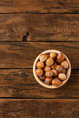 Fresh hazelnuts in bowl on wooden background with copyspace. Top view
