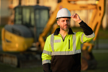 Builder on excavator. Builder worker with excavator. Builder in helmet. Worker in hardhat. Portrait...