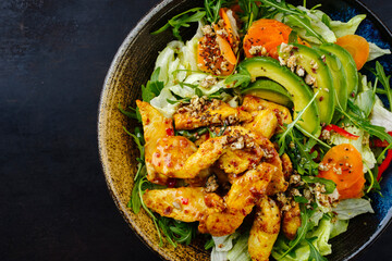 Traditionaler deutscher Eisberg und italienischer Rucola Salat serviert mit Hähnchen, Avocado und Gemüse mit würziger süß sauer Curry Sauce als Draufsicht auf einem rustikalen Teller mit Textfreiraum