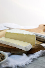 delicious brie cheese with cut slice on wooden plate with copy space