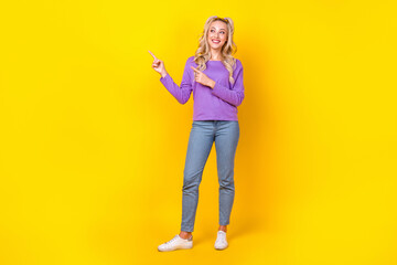 Full length photo of lovely young lady fingers point look empty space wear trendy purple garment isolated on yellow color background