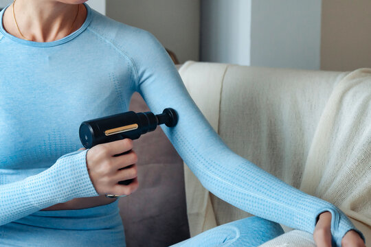 Applying Therapeutic Percussive Massager Gun At Home. Crop Image Sporty Woman Doing Vibration Percussion Massage Arms Self-massaging. Gun Shock Therapy. Medical Recovery Concept. Copy Ad Text Space