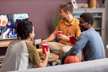 Fototapeta Diverse group of men watching sports match on TV at home and drinking beer obraz