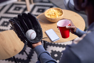 Close up of sports fan wearing baseball glove while watching match at home, copy space