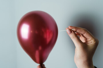 Woman Holding a Needle Close to a Balloon to Pop