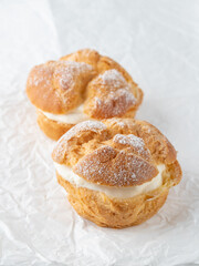 Cream puffs, pastry from choux covered  sugar powder on white paper.