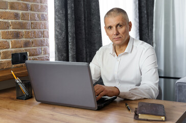 Portrait of middle aged business man working at home with laptop.