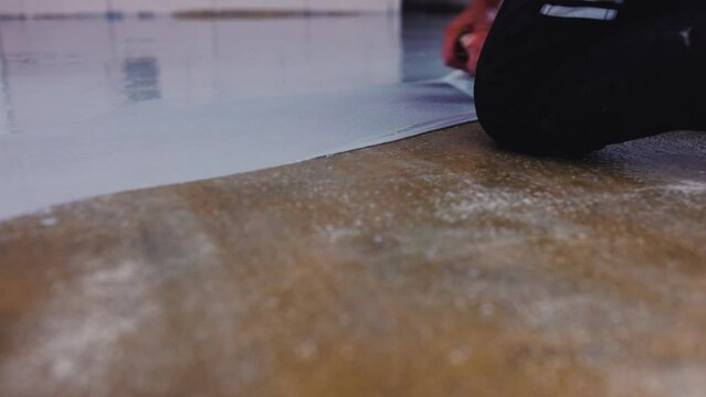 Worker aply one type of flooring that is created by coating a concrete floor with a mixture of epoxy resin and hardener. 
