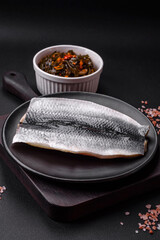 Delicious salted herring fillet in oil on a black ceramic plate
