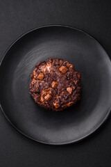 Delicious fresh oatmeal round cookies with chocolate on a black ceramic plate