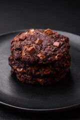 Delicious fresh oatmeal round cookies with chocolate on a black ceramic plate