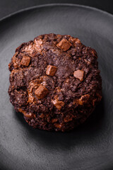 Delicious fresh oatmeal round cookies with chocolate on a black ceramic plate