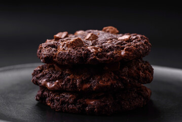 Delicious fresh oatmeal round cookies with chocolate on a black ceramic plate