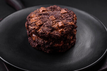 Delicious fresh oatmeal round cookies with chocolate on a black ceramic plate
