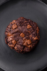 Delicious fresh oatmeal round cookies with chocolate on a black ceramic plate
