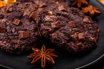 Delicious fresh oatmeal round cookies with chocolate on a black ceramic plate