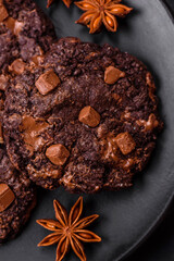 Delicious fresh oatmeal round cookies with chocolate on a black ceramic plate