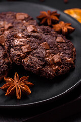 Delicious fresh oatmeal round cookies with chocolate on a black ceramic plate