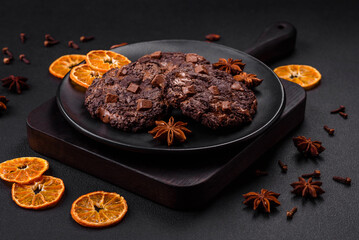 Delicious fresh oatmeal round cookies with chocolate on a black ceramic plate