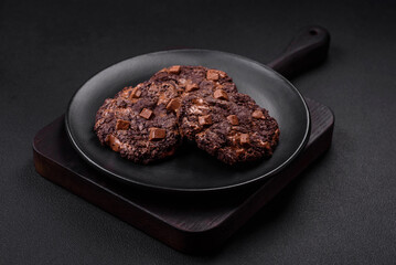 Delicious fresh oatmeal round cookies with chocolate on a black ceramic plate