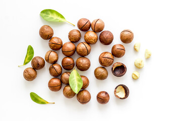 Pile of raw macadamia nuts with leaves. Healthy protein snack background