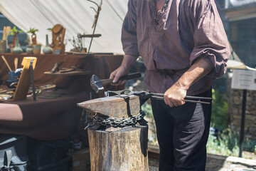 Caucasian male blacksmith forges iron in an anvil. - Powered by Adobe