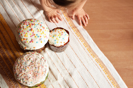 Festive Easter cakes with white icing and sprinkling, festive composition. The hand of a child, The image of family and home comfort.