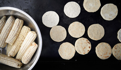 Corn tortillas made by a elderly woman in a hot griddle