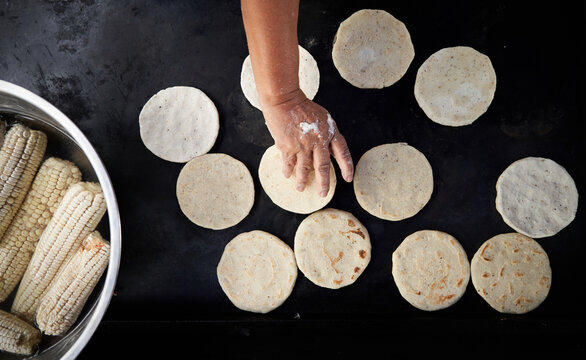 Corn tortillas made by a elderly woman in a hot griddle