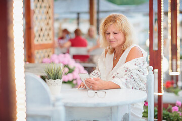 Portrait of a young woman drinking beer on the terrace of a beach cafe on a summer sunny day