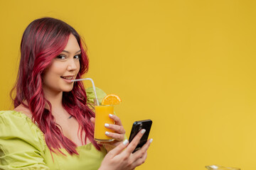 a beautiful young redhead in a green dress is drinking orange juice