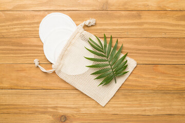 Eco cotton pads with sack on wooden background, top view