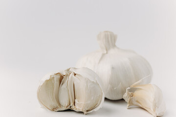 Halbe Knoblauchzehe weiß mit herausgelöster ungeschälter Knoblauchzehe und Knoblauchknolle im...