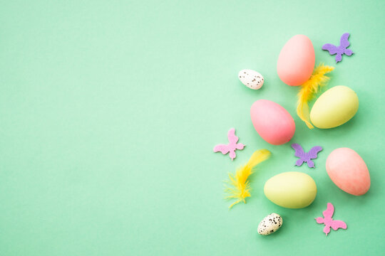 Happy Easter background with colored eggs and butterflies. Flat lay image at green.