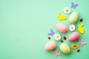 Fototapeta na wymiar Happy Easter background. Eggs, rabbit, spring flowers and butterfly. Flat lay image at green background.