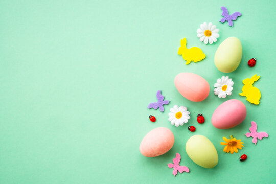 Happy Easter background. Eggs, rabbit, spring flowers and butterfly. Flat lay image at green background.