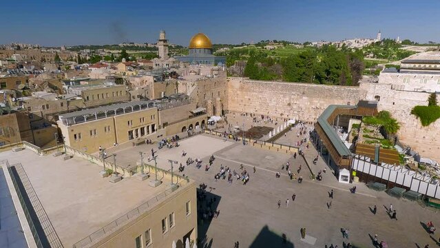 The Jewish shrine of the Wailing Wall in the old city of Jerusalem against the backdrop of the Al-Aqsa Mosque and many people. Top view of the historic city center of Jerusalem. High quality 4k
