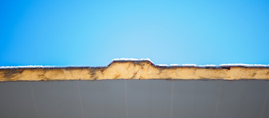 Roof insulated with sandwich panels and covered with winter frost